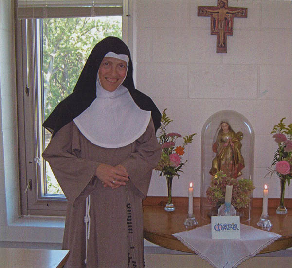 Sister standing before statue of St. Clare.