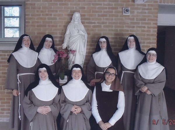 Poor Clare Nuns gathered before statue of Jesus.